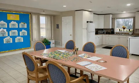 Activity room with a puzzle table, chairs and a kitchenette.