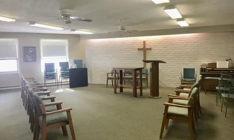 Chapel with rows of chairs, a lectern and a cross.