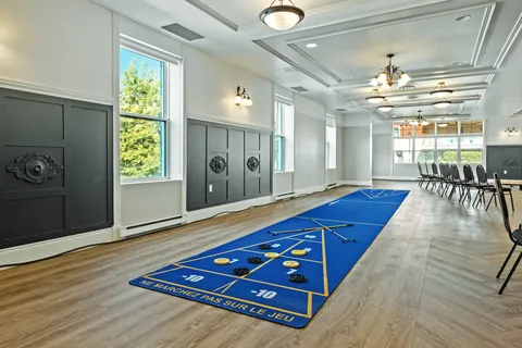 Indoor shuffleboard mats beside windows and rows of folding chairs
