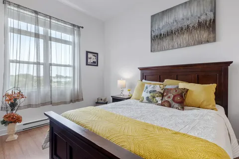 Bedroom with a wooden bed, yellow bedding, floral cushions and a window