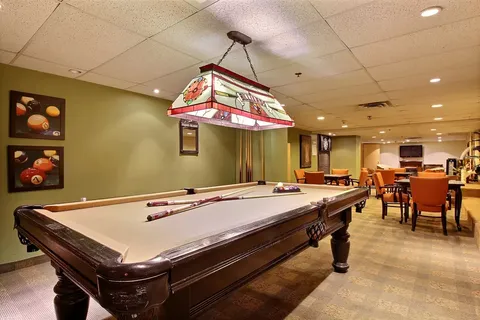 Pool table beneath a stained-glass light with tables and chairs beyond