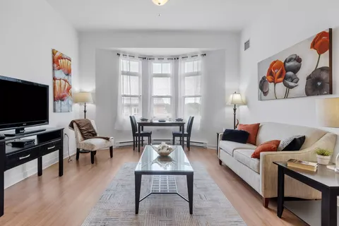 Sitting area with a sofa, television, coffee table and dining table by a window