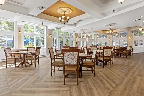 Dining room with wooden chairs, round tables, broad windows and chandeliers