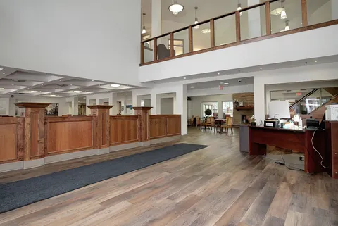 Lobby with a wooden reception counter, open staircase and upper-level gallery.