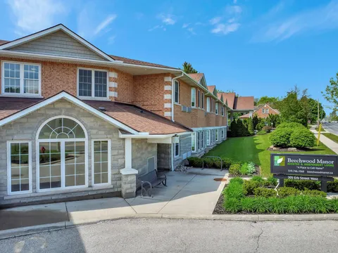 Brick residence exterior with bay windows, a driveway and planted borders.
