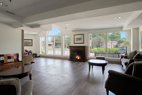 Lounge with a fireplace, sofas, an armchair and windows overlooking a patio.