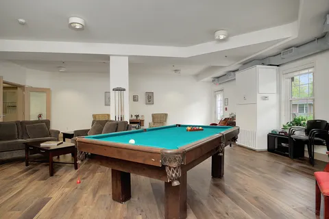 Recreation room with a pool table, sofas and a piano.