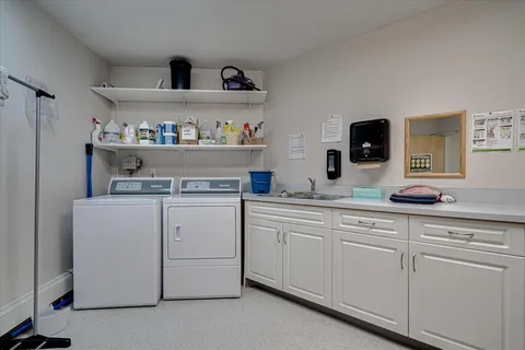 Laundry room with a washer, dryer, sink, cupboards and cleaning supplies