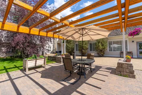 Round patio table with an umbrella beneath a pergola