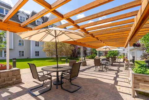 Brick patio with tables, umbrellas and a wooden pergola