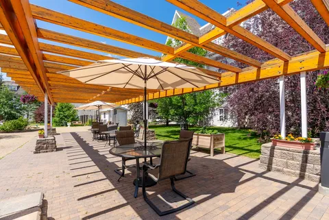 Patio tables and umbrellas beneath a wooden pergola