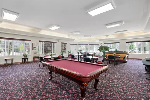 Games room with a red pool table and tables by the windows