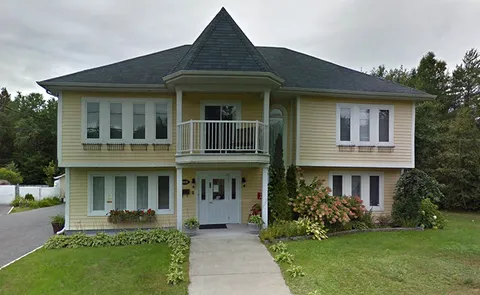 Two-storey residence with a central entrance, balcony and front lawn.