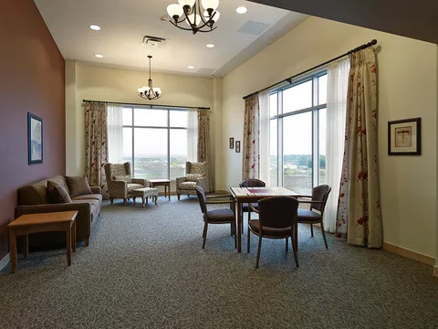Room with upholstered armchairs, a table and framed landscape pictures