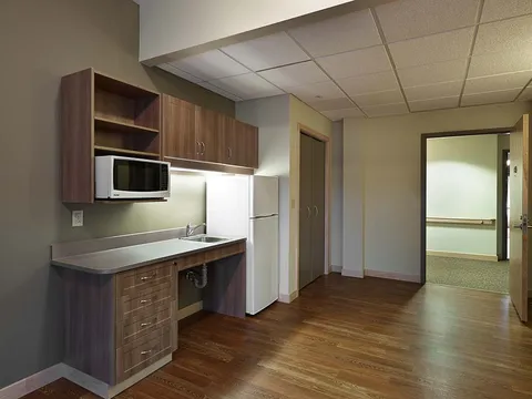 Empty room with a kitchenette, wooden cupboards and a refrigerator