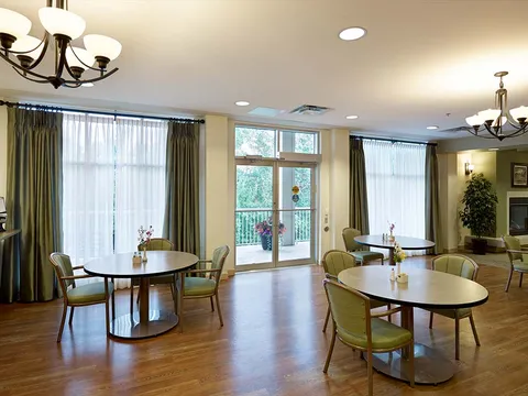 Room with small dining tables, chairs and a glass door to a balcony