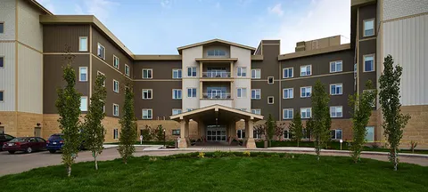 Multi-storey building with an entrance canopy, lawns and planted beds