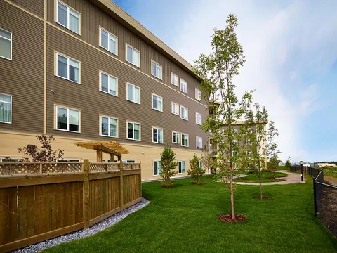 Side of a residential building beside a lawn and young trees