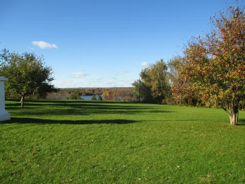 Open lawn overlooking water and autumn trees
