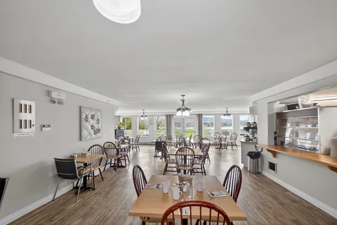 Dining room with wooden tables, chairs and windows overlooking a lawn