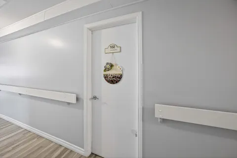 White door numbered 102 beside a wall rail