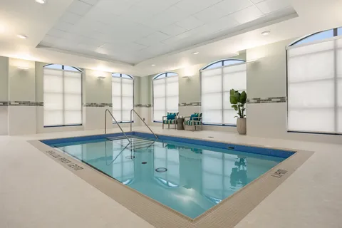 Indoor swimming pool with tall arched windows.