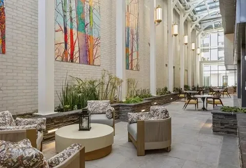 Atrium lounge with tall windows, planted beds and seating.