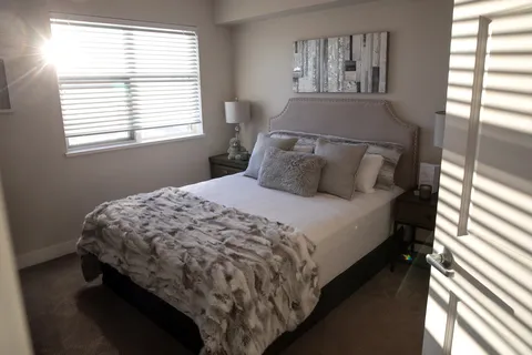 Bedroom with patterned bedding, a bedside lamp and framed birch-tree art