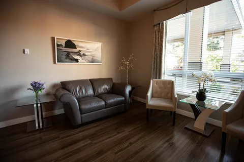Leather sofa and two pale chairs beside glass tables and a framed beach picture