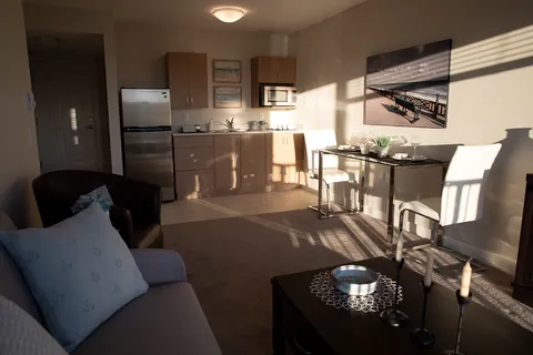 Suite with a sofa, armchair, kitchenette, dining table and framed pier picture