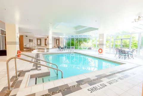 Indoor swimming pool with metal handrails beside large windows