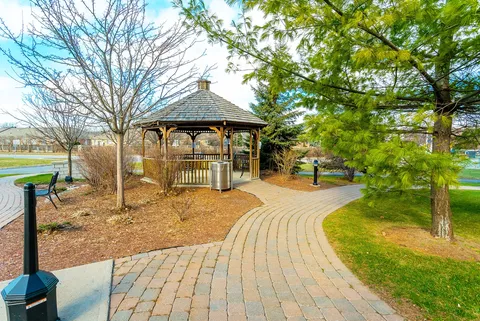 Paved path curving around a gazebo, trees and lawn