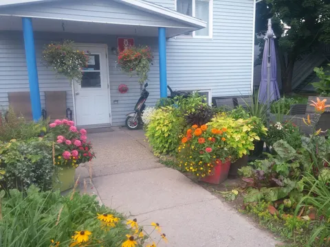 Entrance with blue posts, hanging baskets and pots of pink and orange flowers