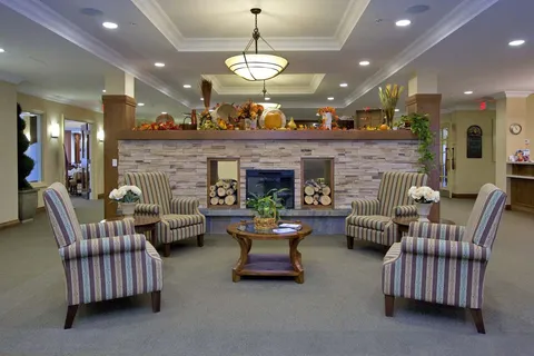 Sitting area with striped armchairs around a coffee table and a stone fireplace