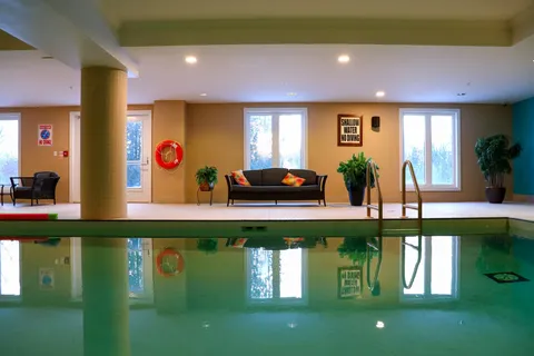 Indoor swimming pool with a ladder, life ring, seating and potted plants