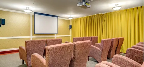 Room with rows of armchairs facing a blank projection screen