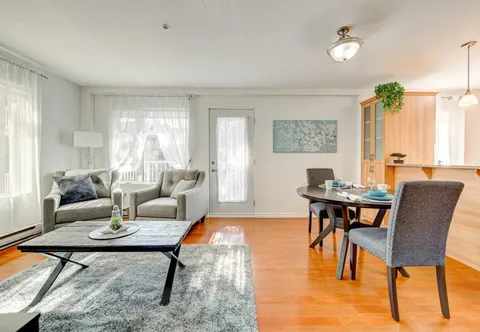Apartment sitting and dining area with armchairs, a coffee table and tall windows