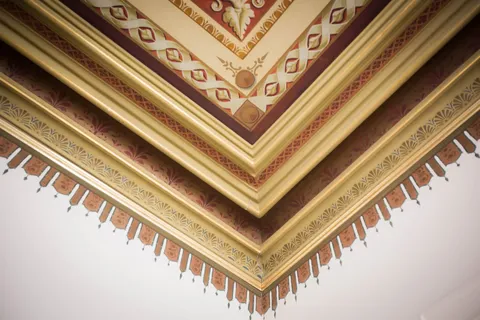 Corner of an ornate ceiling with painted geometric and floral patterns