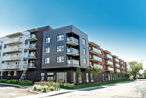 Multi-storey residence with balconies beside a landscaped driveway