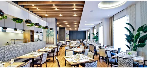 Dining room with long wooden tables, upholstered chairs and pendant lights
