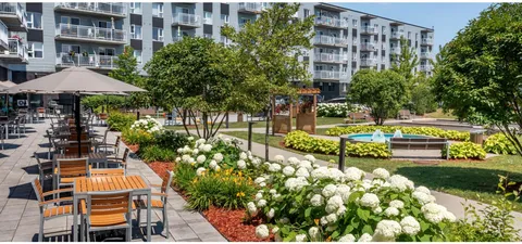 Garden courtyard with flowers, a path and covered seating beside balconies