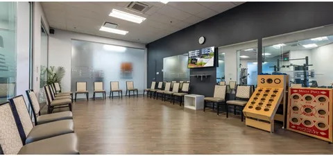 Activity room with rows of chairs and wooden games beside a wall-mounted television