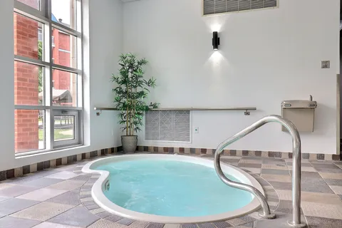 Indoor whirlpool with a handrail beside windows