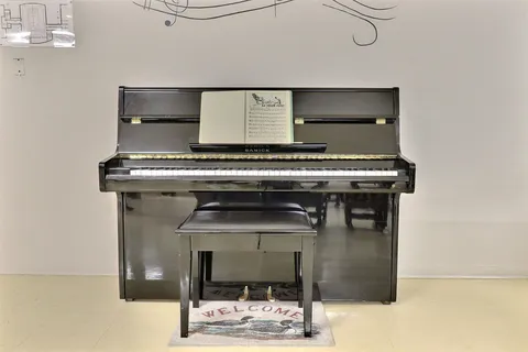 Upright piano and matching bench against a white wall