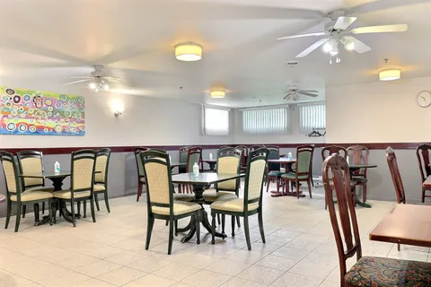 Room with round tables, wooden chairs, ceiling fans and colourful abstract artwork