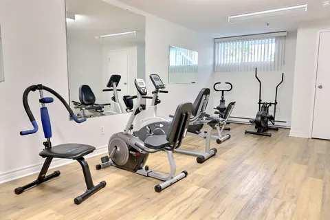 Exercise room with stationary bikes, a mirror and windows