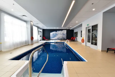 Indoor swimming pool with windows along one wall.