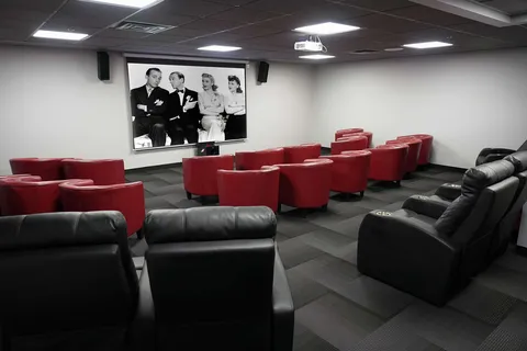 Screening room with rows of red and black armchairs.