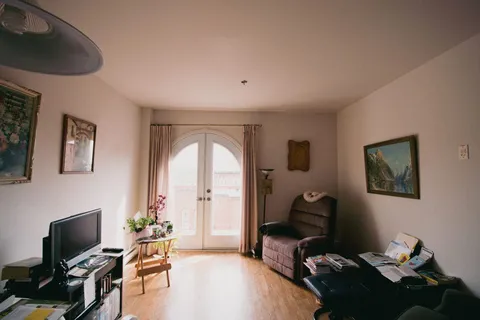 Furnished living room with armchairs and glass balcony doors.
