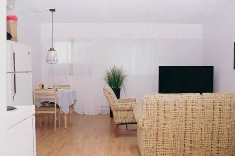 Apartment living area with wicker seating, television and dining table.